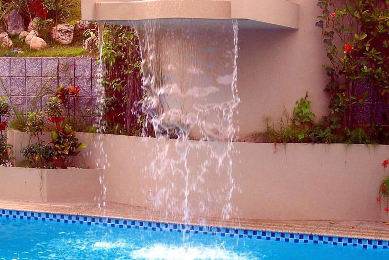 A waterfall is falling into a swimming pool