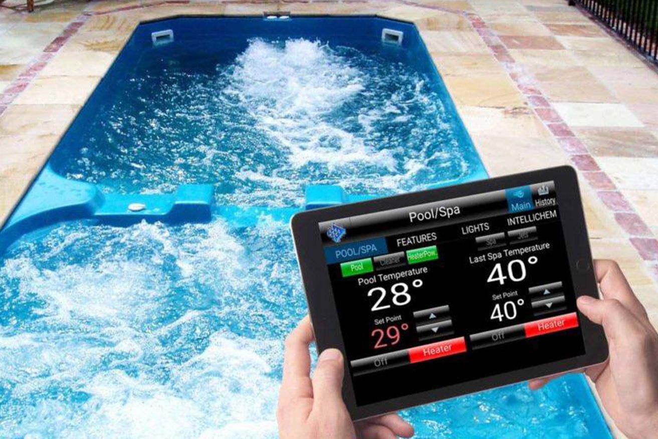 A person is holding a tablet in front of a swimming pool.