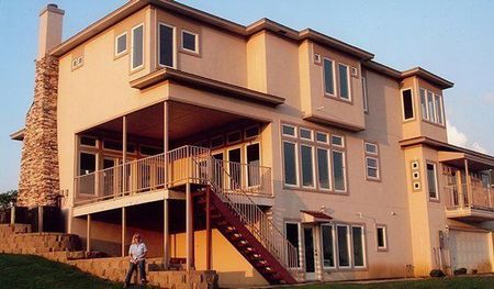 Red excavator digging next to a yellow house, outdoors.