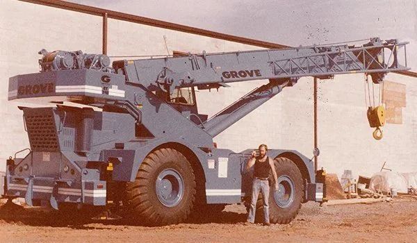 Large blue Grove crane with a man standing next to it.
