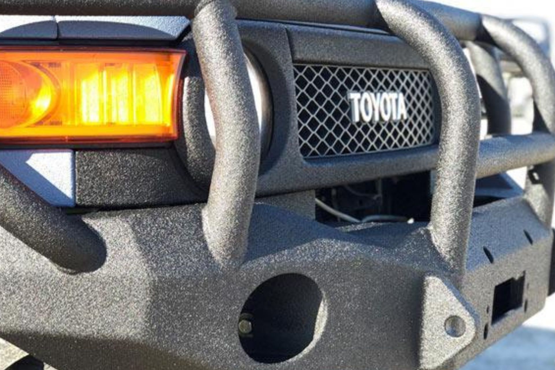 Close-up of a black Toyota FJ Cruiser bumper with guard and headlight.