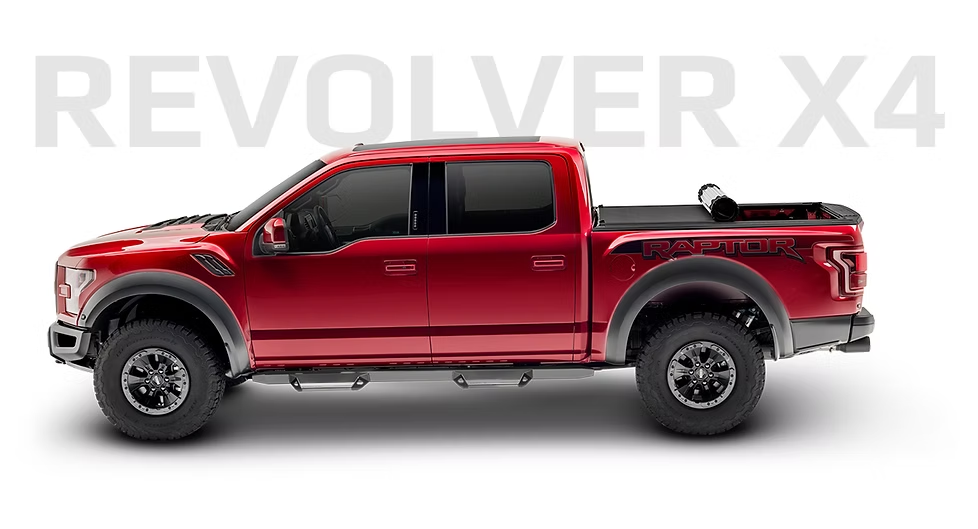 Red Ford Raptor truck with REVOLVER X4 text. Truck has a black tonneau cover.