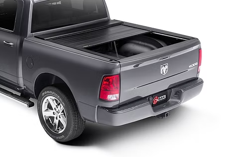 A gray pickup truck with a black retractable tonneau cover. The truck is parked outdoors, at a slight angle.