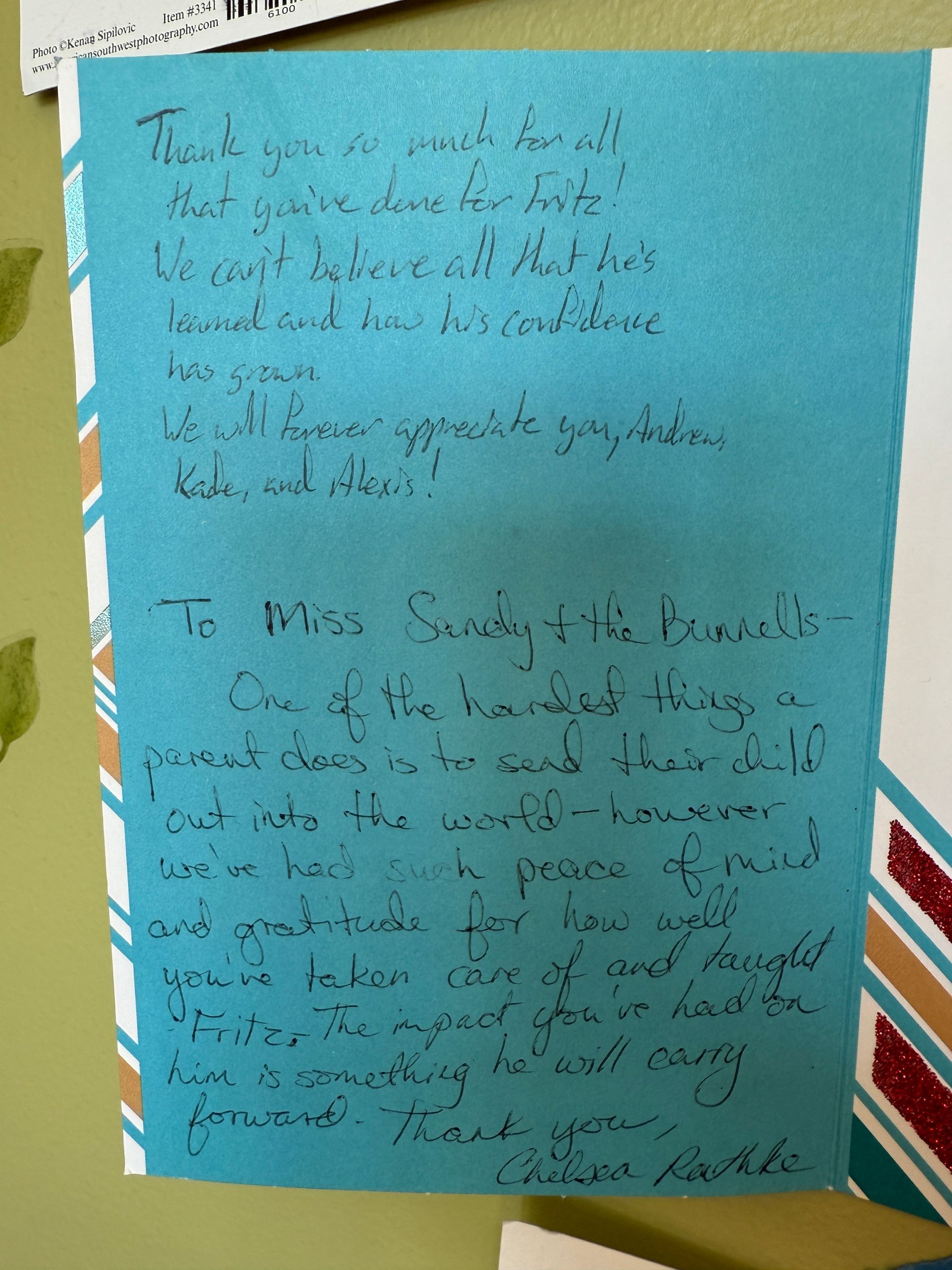 Blue card with handwritten text, thanking someone. The card has a decorative striped border.