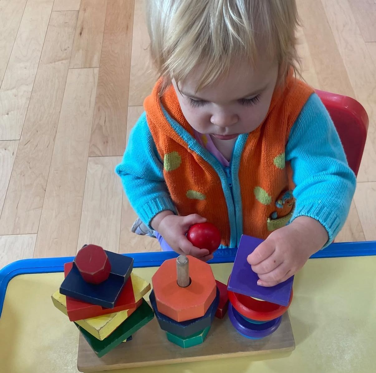 Child playing with colorful wooden shape sorter. Child focused.