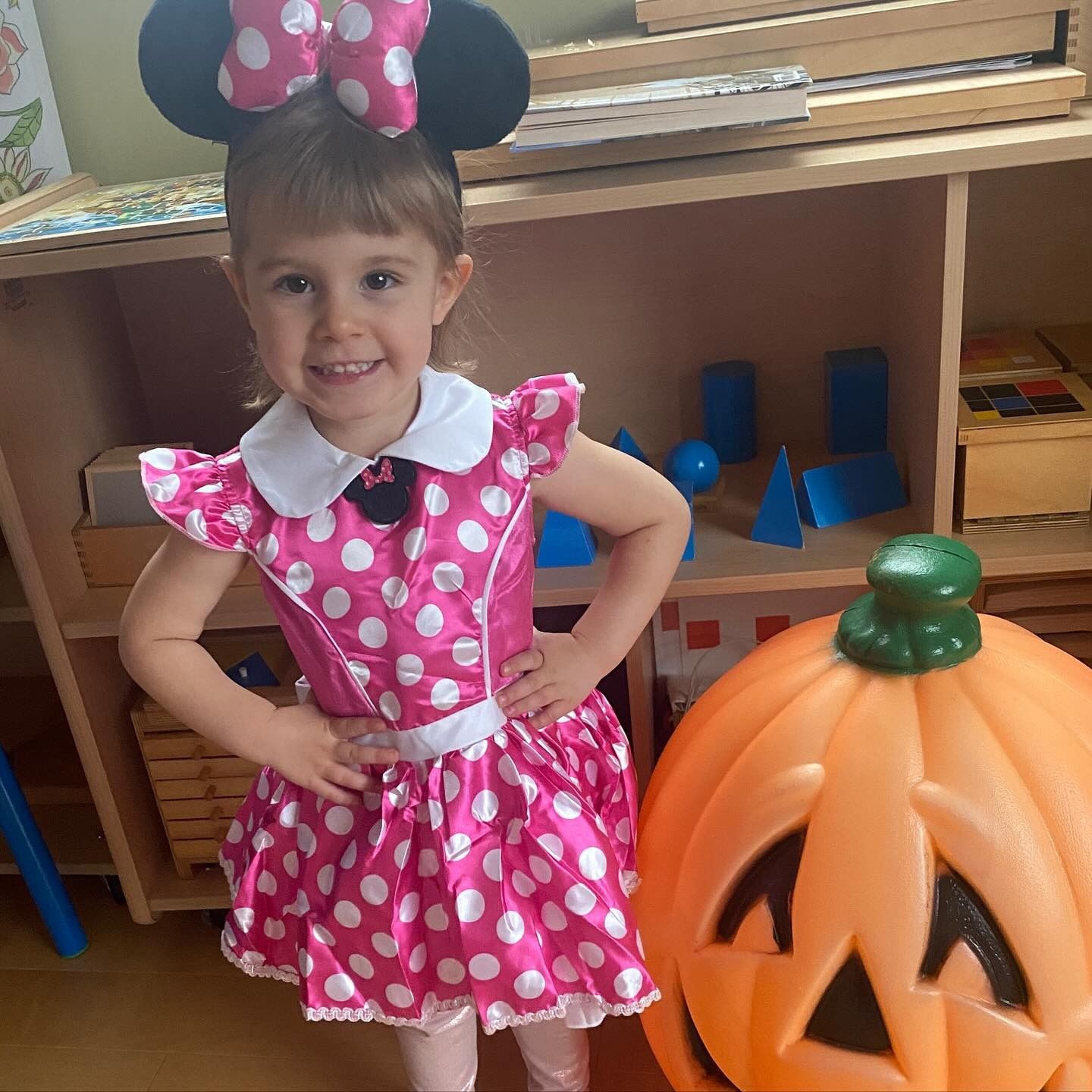 Girl in Minnie Mouse costume with pumpkin.
