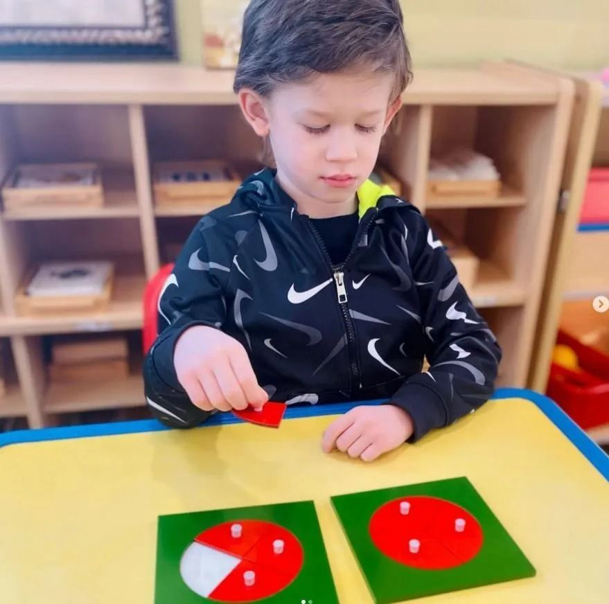 Boy at table with shape puzzles, focusing on a red square. Educational setting.