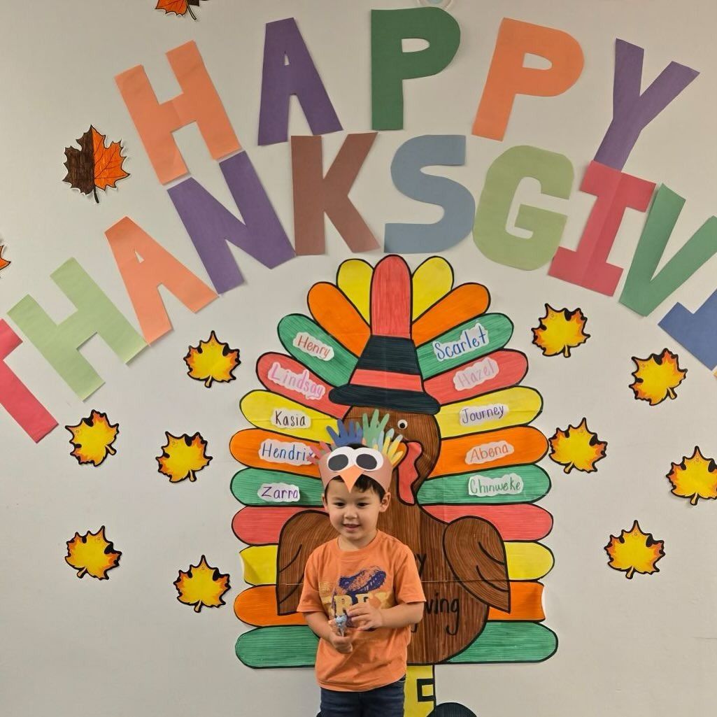 Boy in a turkey hat in front of a wall with 