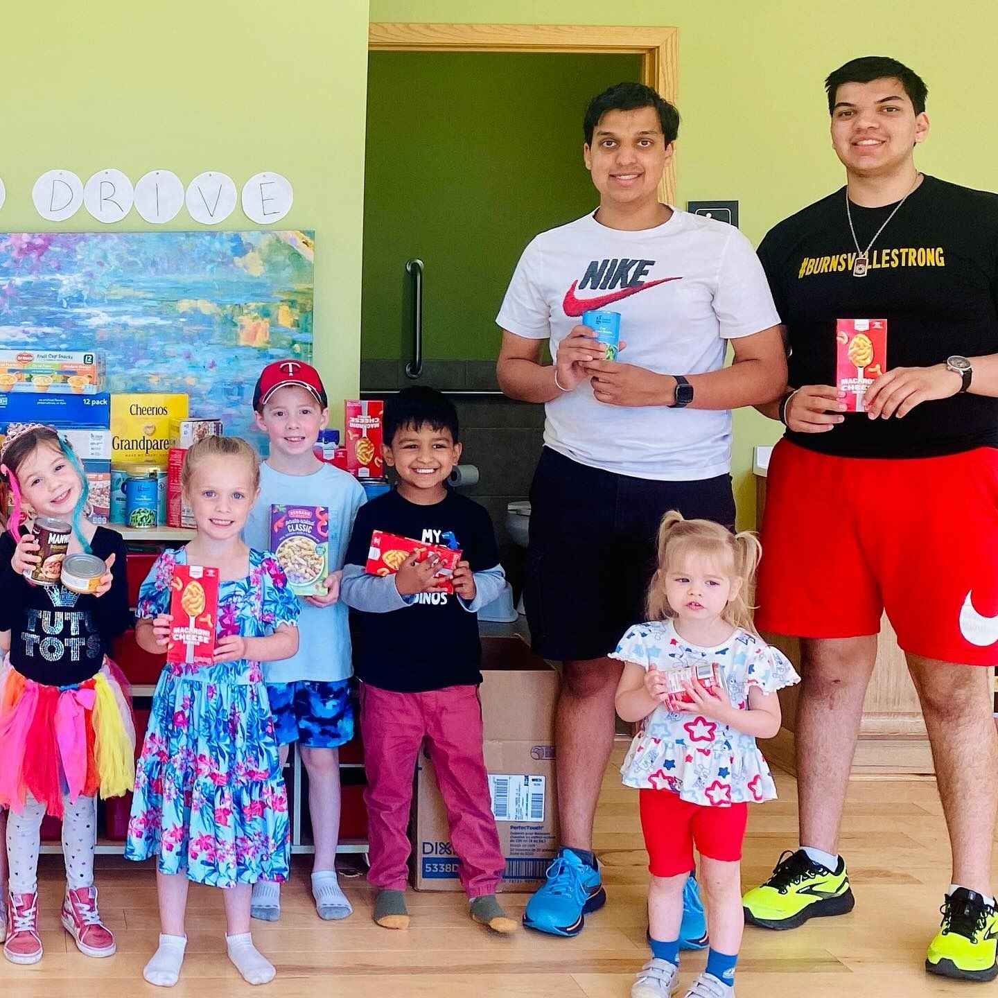 Group of people holding packaged food items in a brightly lit room.