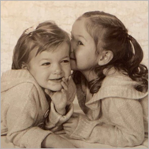 Two young girls whispering secrets; sepia tone.