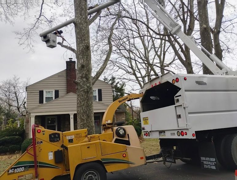 A tree chipper is cutting a tree in front of a house.