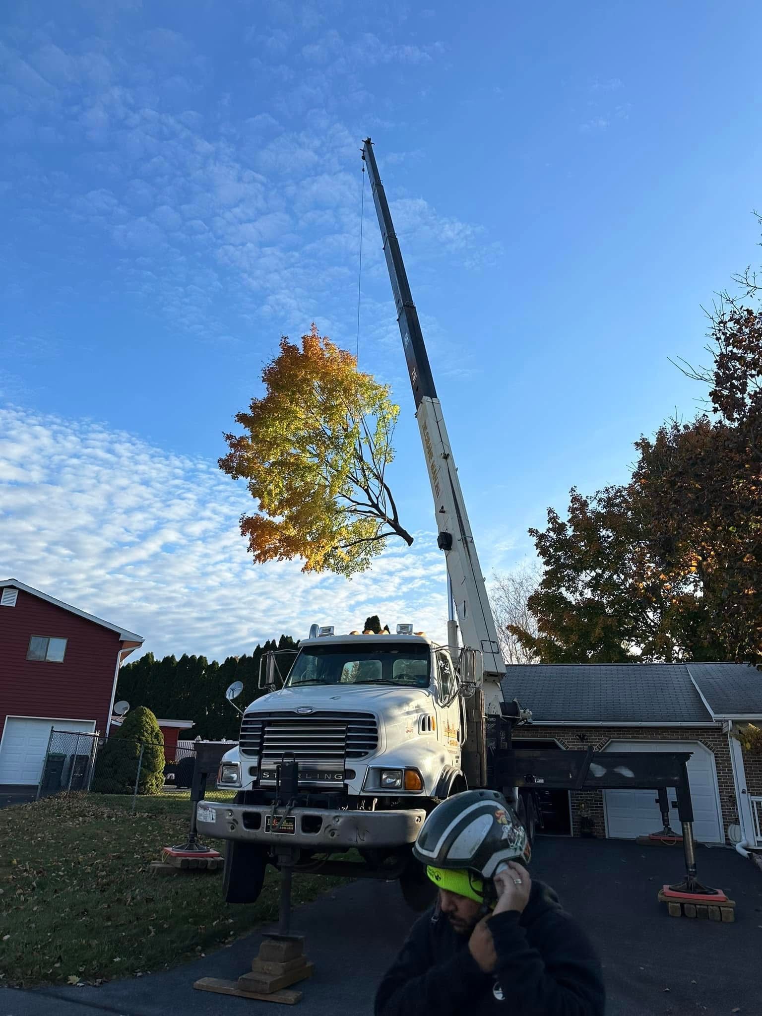 A man wearing a helmet is standing in front of a truck with a crane attached to it.