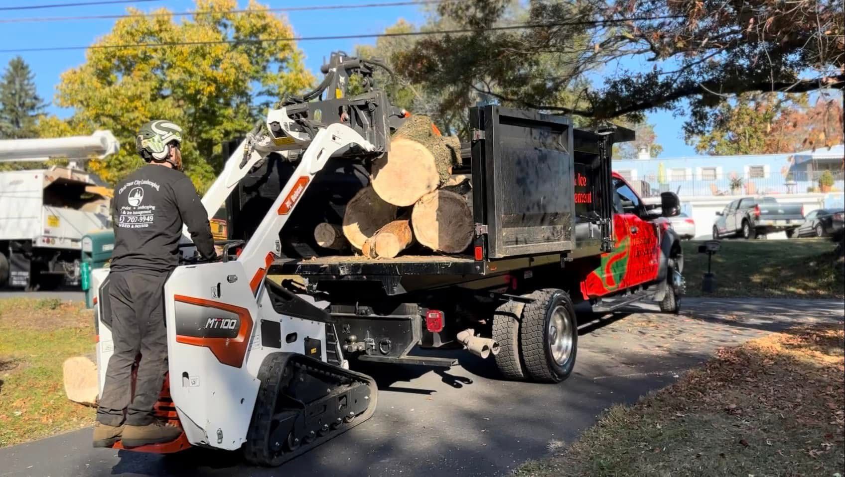 A man is loading logs into a truck.