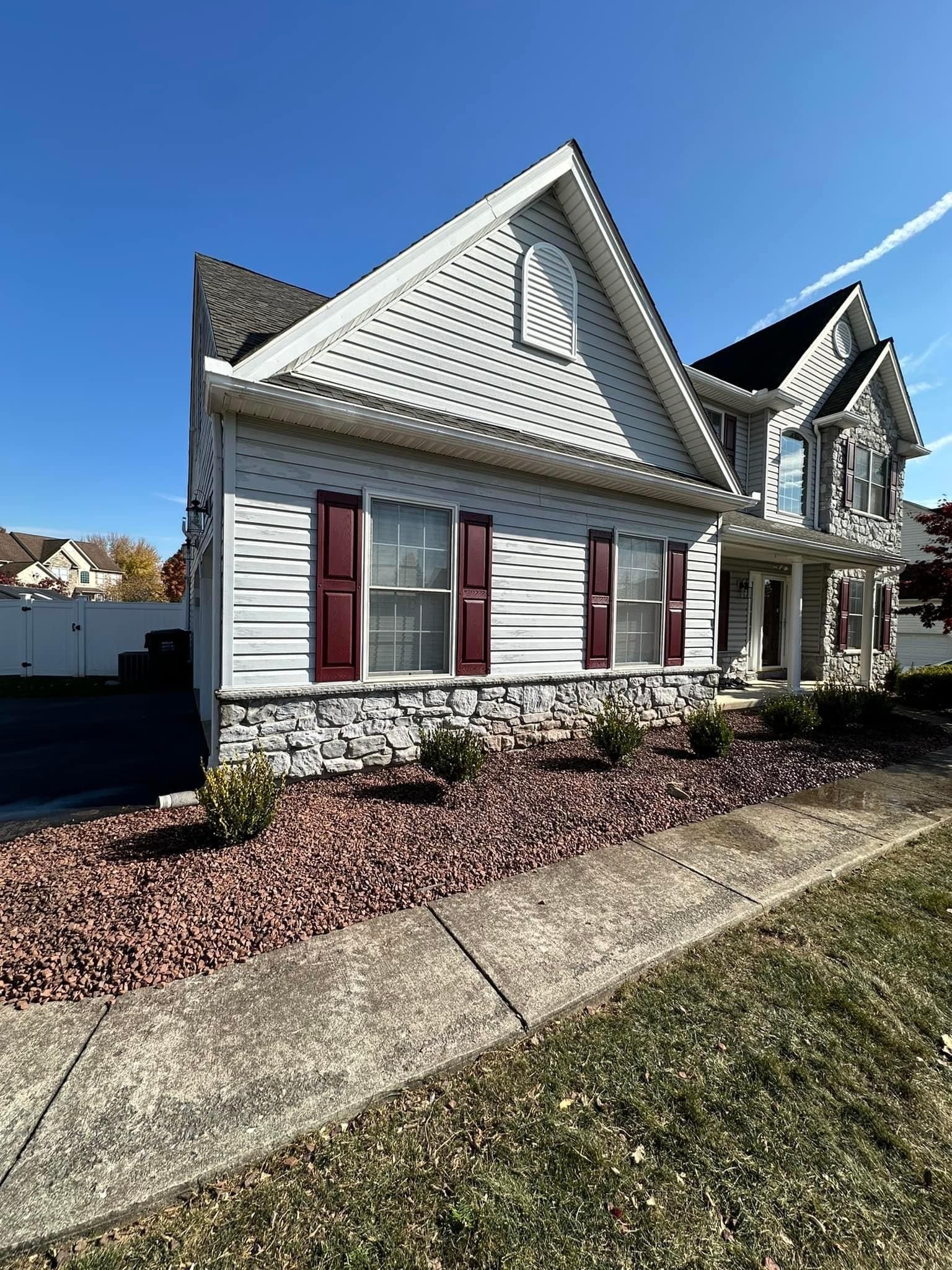 A white house with red shutters and a blue sky in the background.