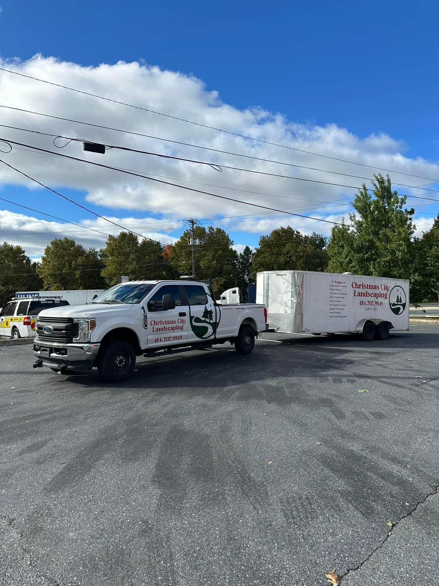 A white truck with a trailer attached to it is parked in a parking lot.