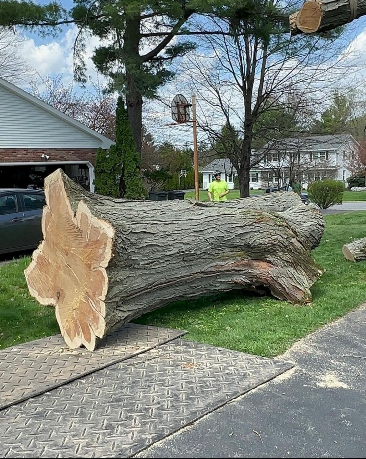 A large tree stump is laying on the sidewalk in front of a house.