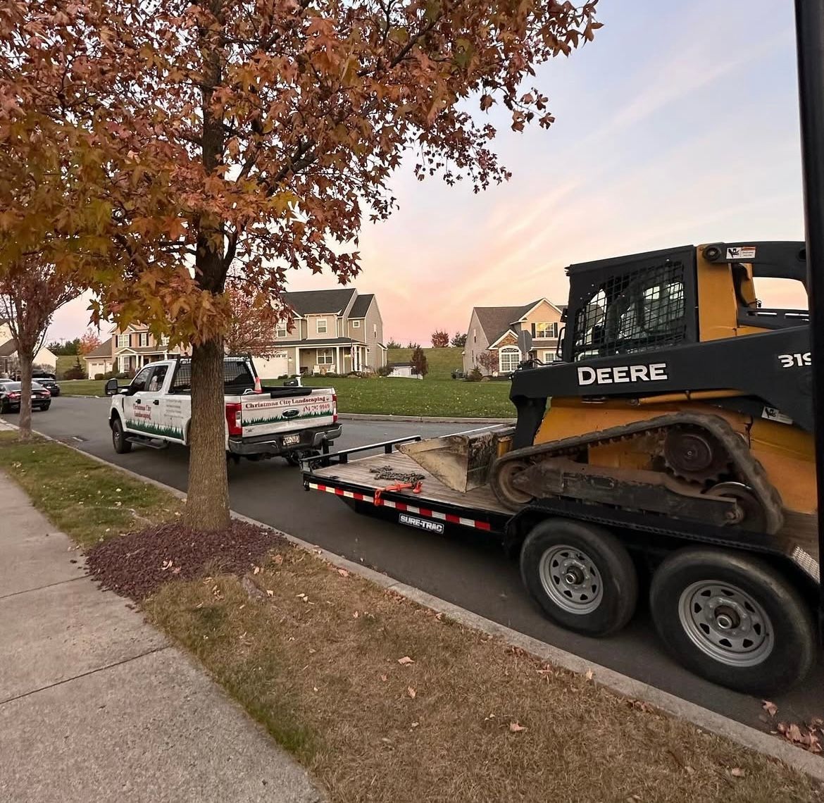 A truck is towing a deere bulldozer on a trailer.