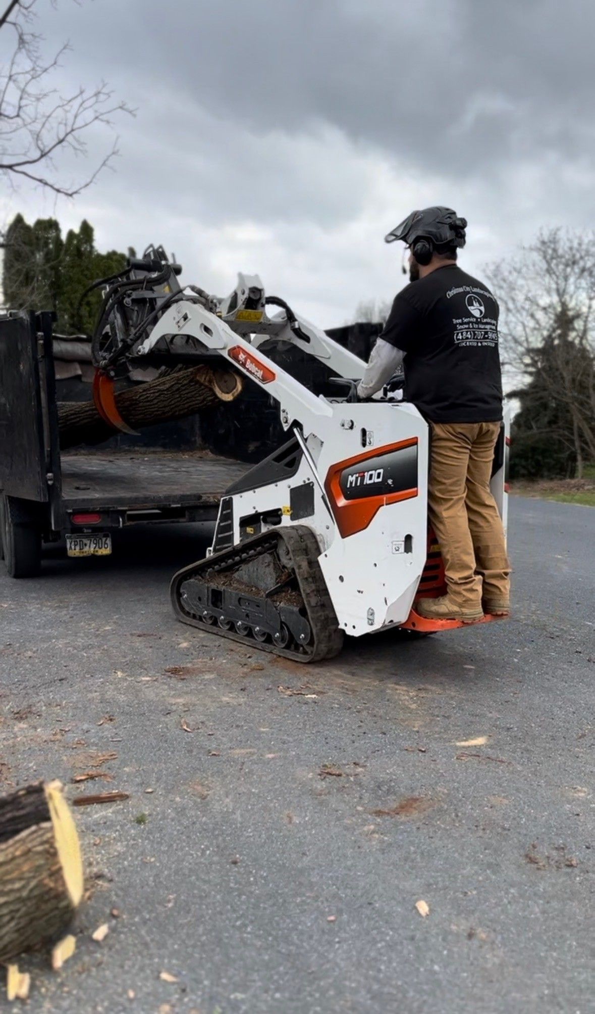 A man is standing next to a bulldozer on the side of the road.