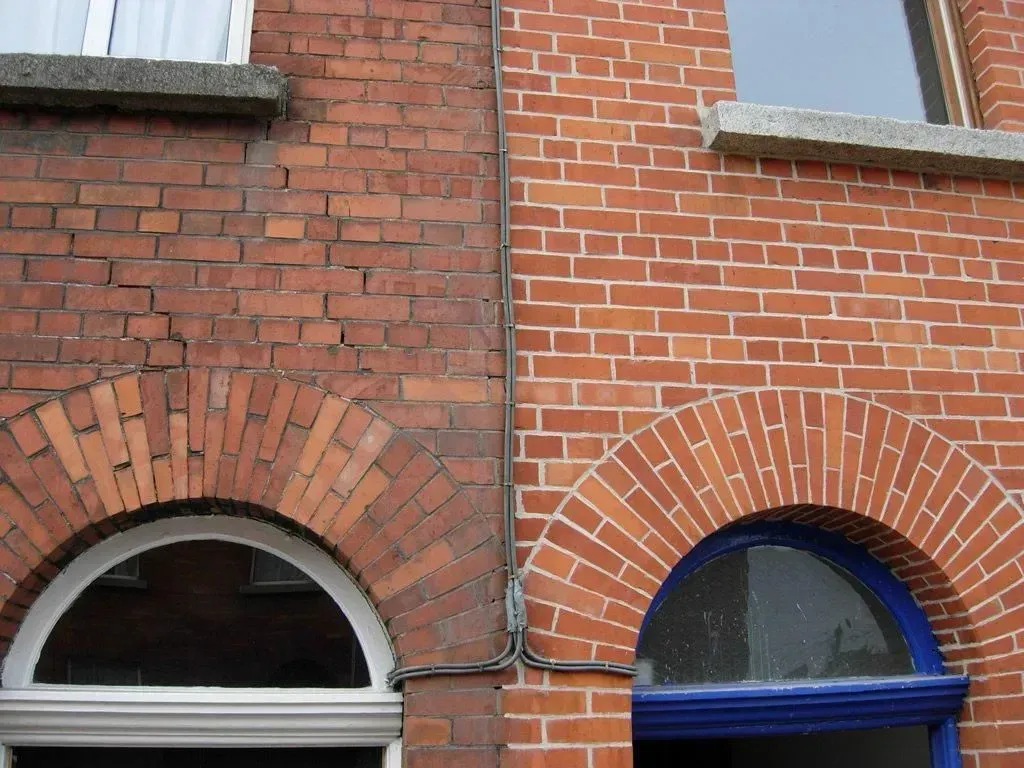 A brick building with two arched windows and a blue door