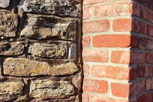A close up of a brick wall next to a stone wall.