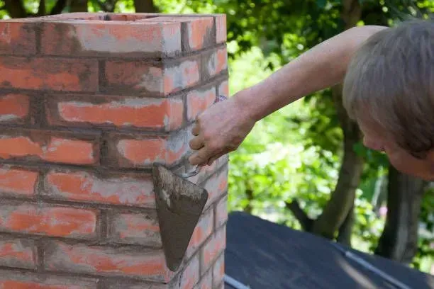 A man is laying bricks on a brick wall with a trowel.