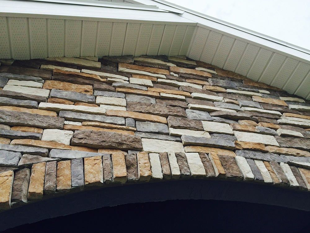 A close up of a stone wall with a roof in the background