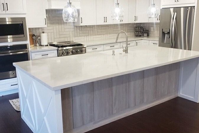 A kitchen with white cabinets , stainless steel appliances , and a large island.