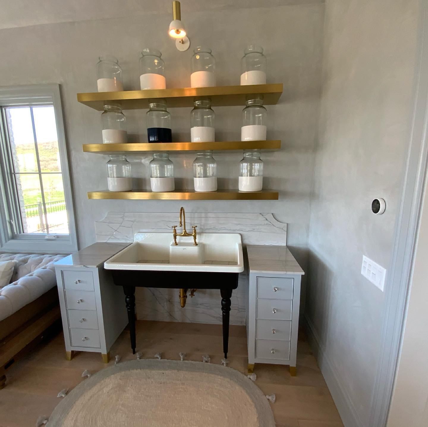 A bathroom with a sink and shelves with jars on them