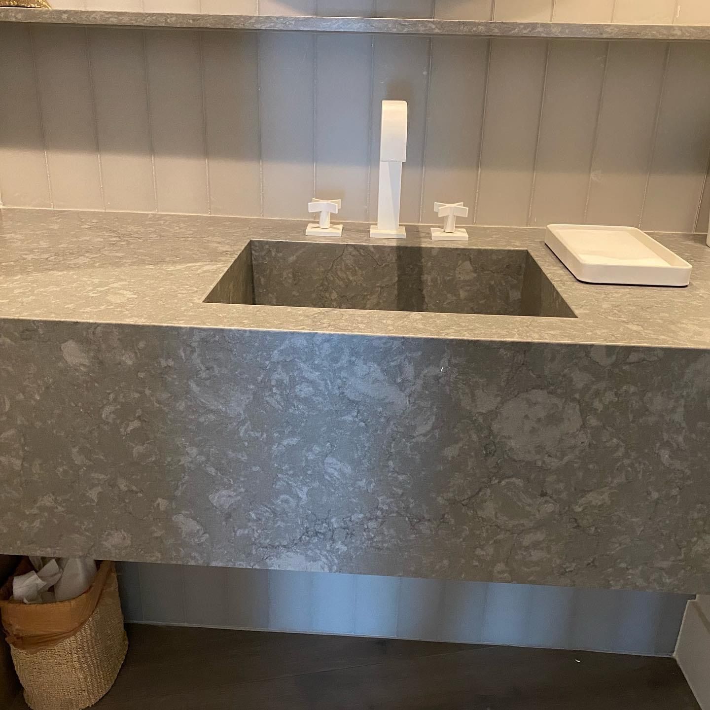 A bathroom sink with a gray counter top and a white faucet.