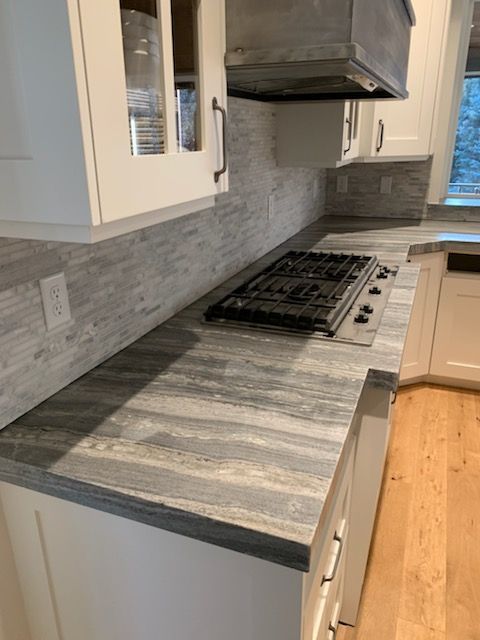 A kitchen with a stove top oven and white cabinets.