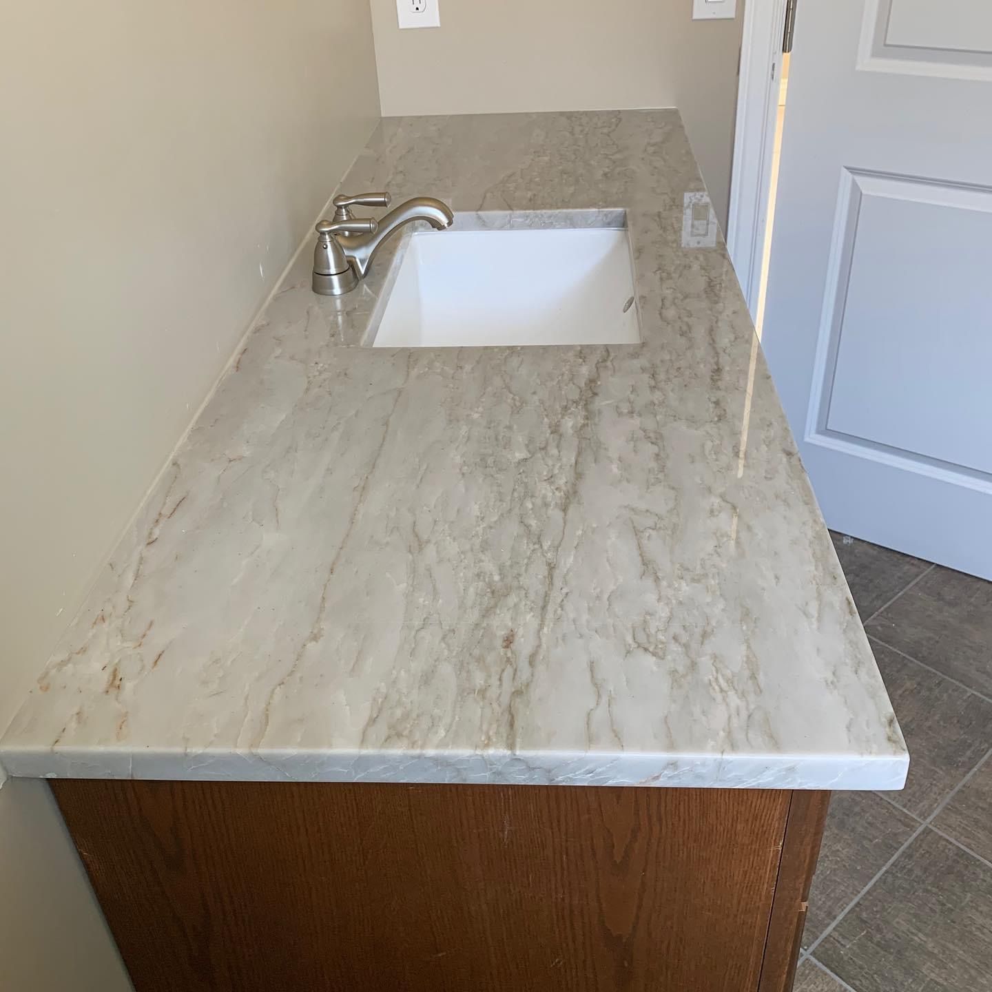 A bathroom sink with a marble counter top and a wooden cabinet.