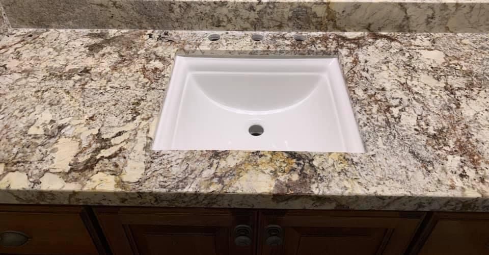 A bathroom sink is sitting on top of a granite counter top.