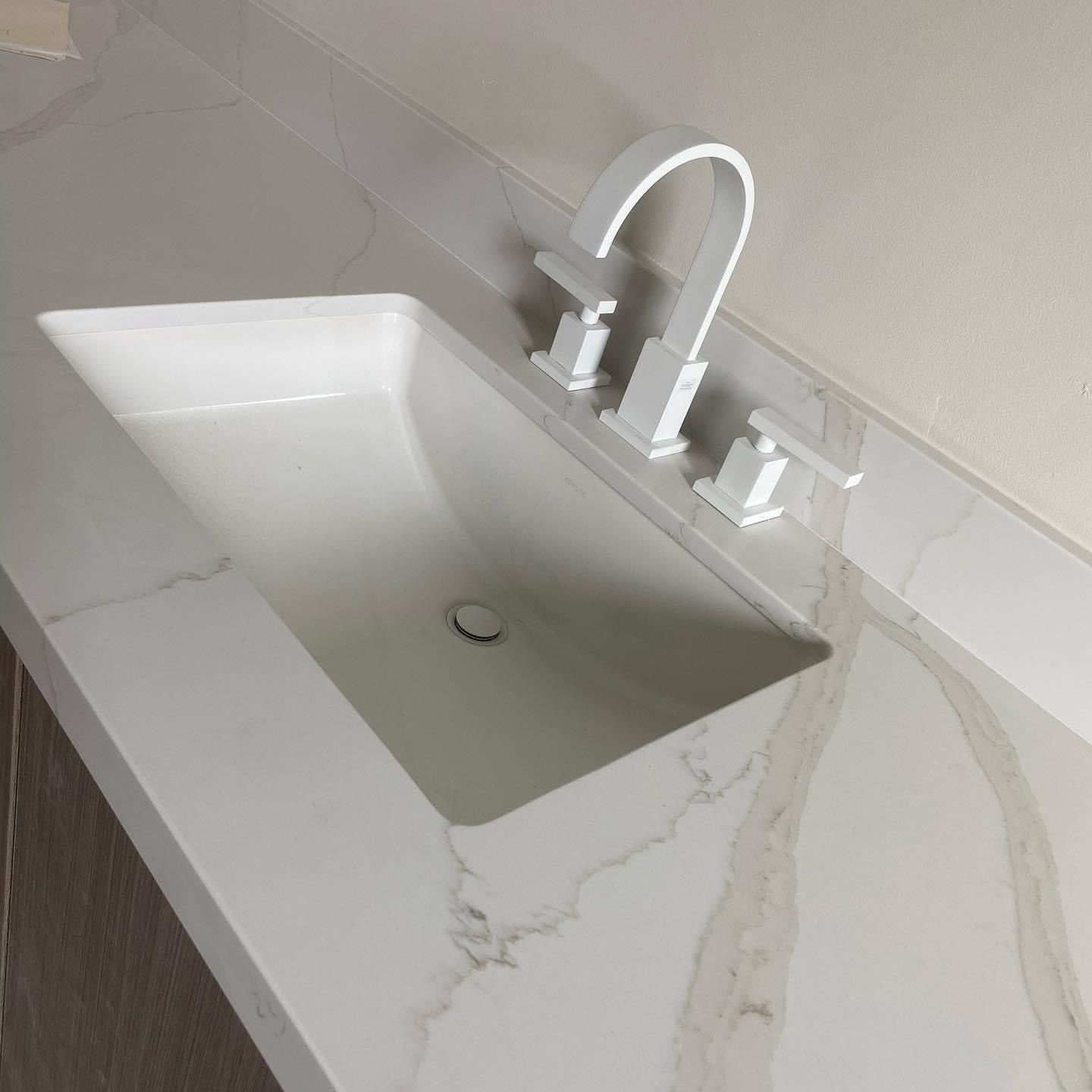 A bathroom sink with a white faucet on a white counter top.