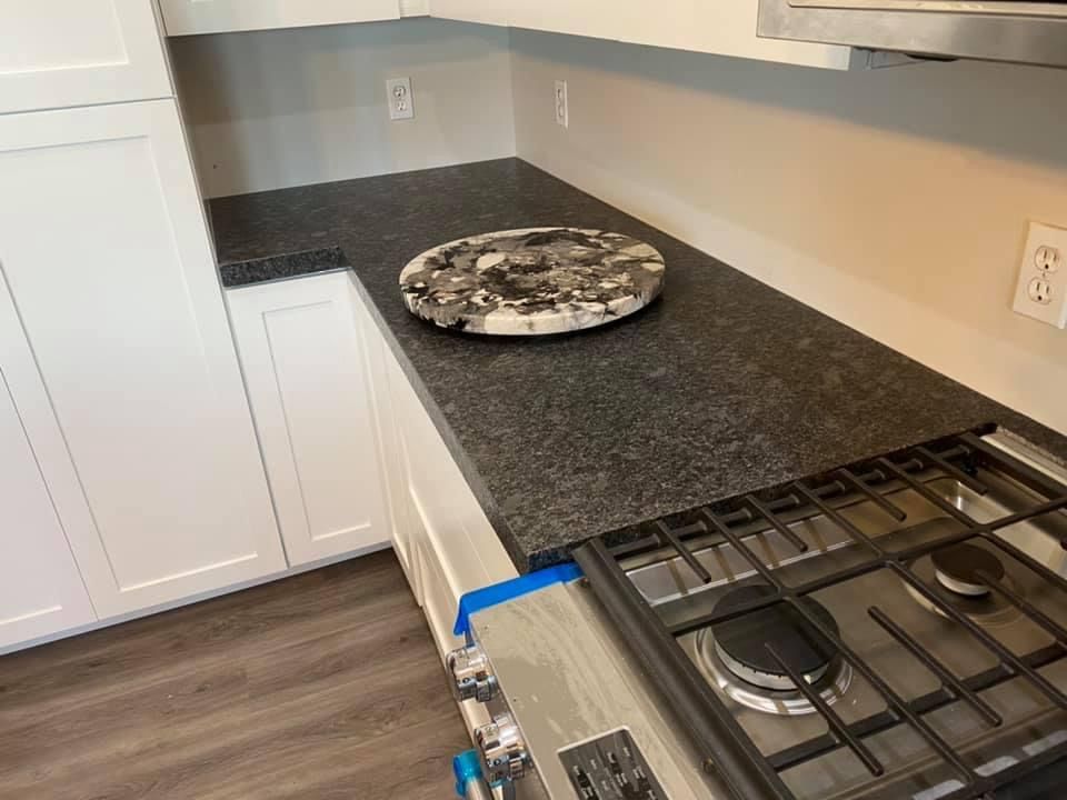A kitchen with a stove top oven and a black granite counter top.
