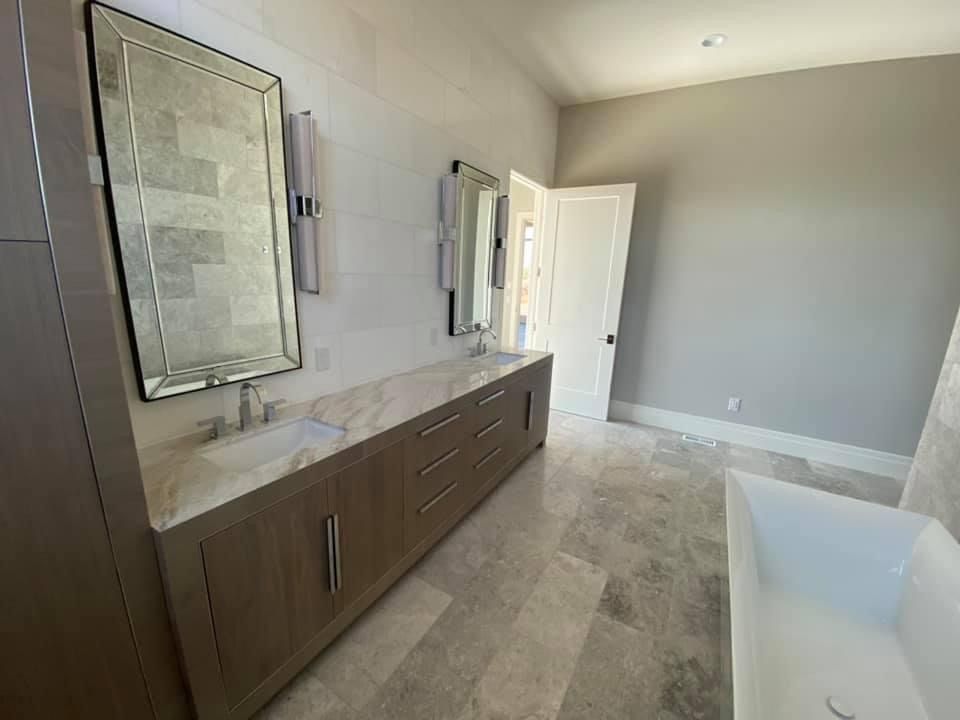 A bathroom with two sinks , two mirrors and a bathtub.