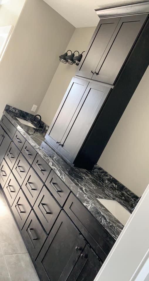 A bathroom with black cabinets and granite counter tops.