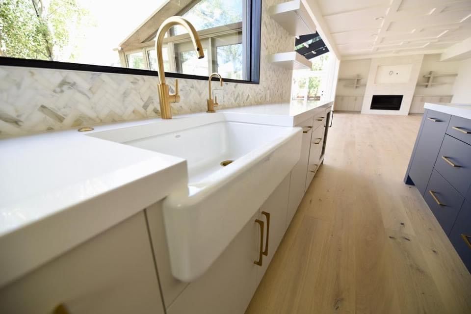 A kitchen with a white sink and a gold faucet