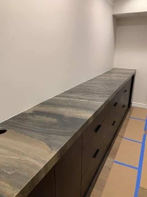 A kitchen with a long counter top and drawers.