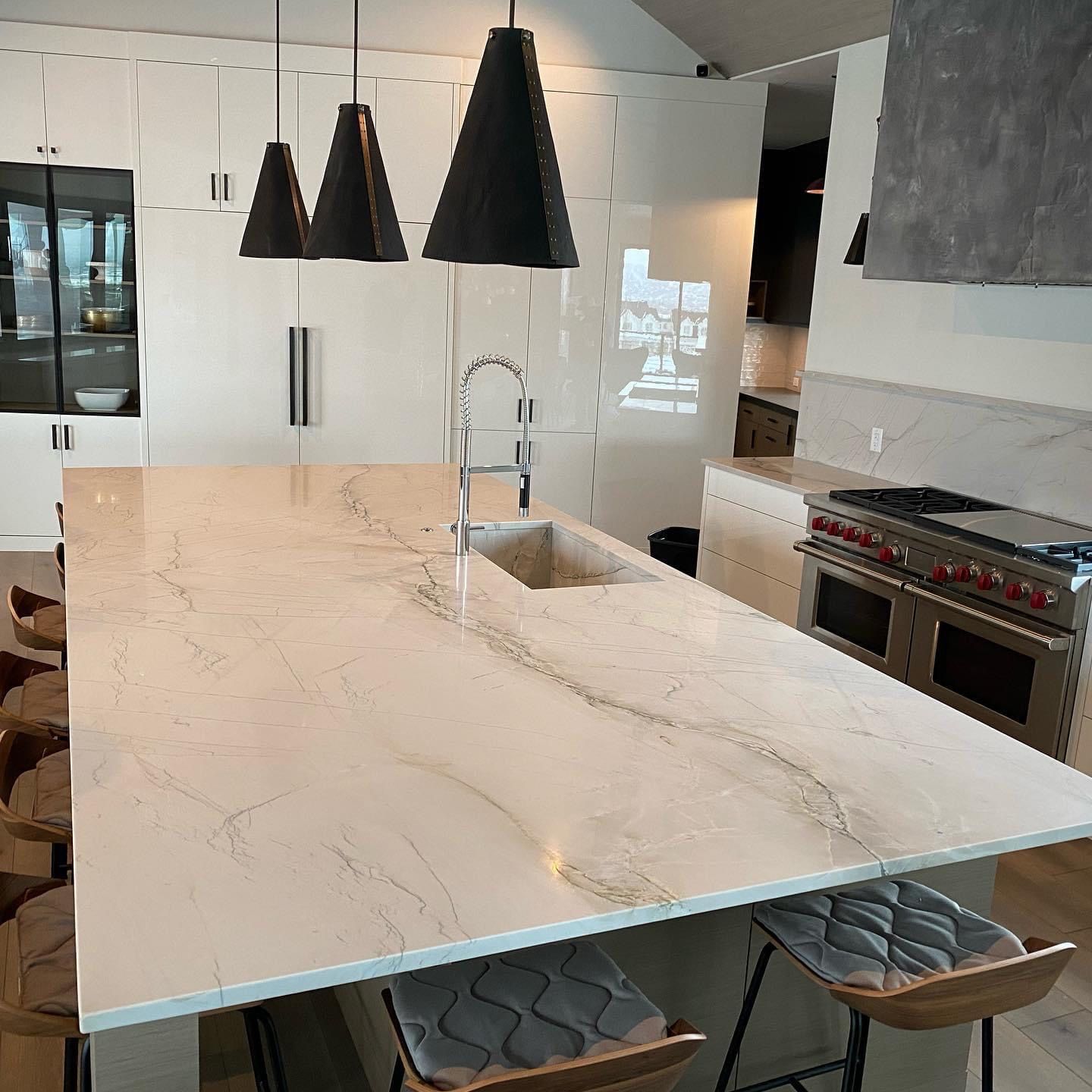A kitchen with a large island , sink , stove and stools.