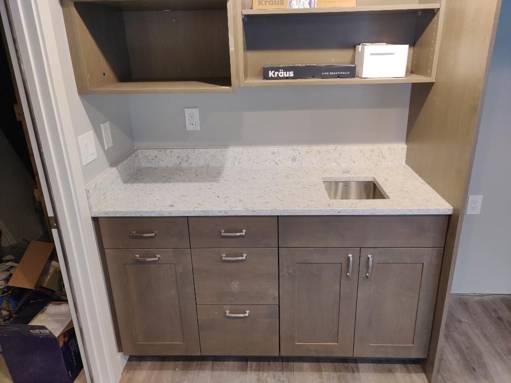 A kitchen with a sink , cabinets , and shelves.