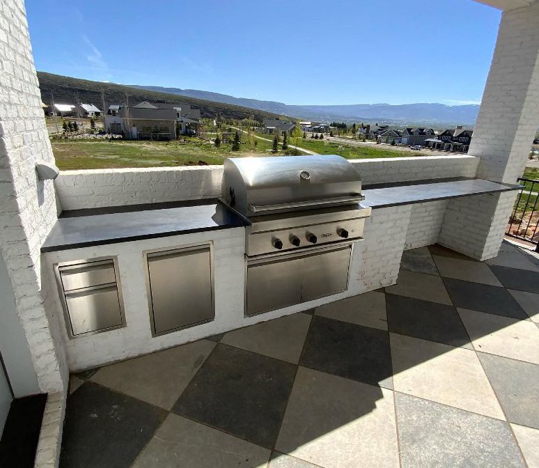 A patio with a grill and a view of mountains