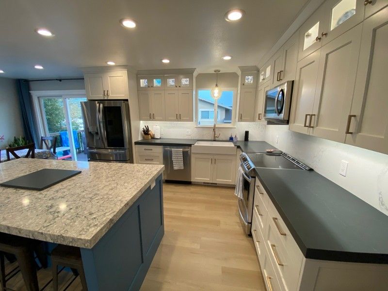 A kitchen with white cabinets , granite counter tops , stainless steel appliances and a large island.