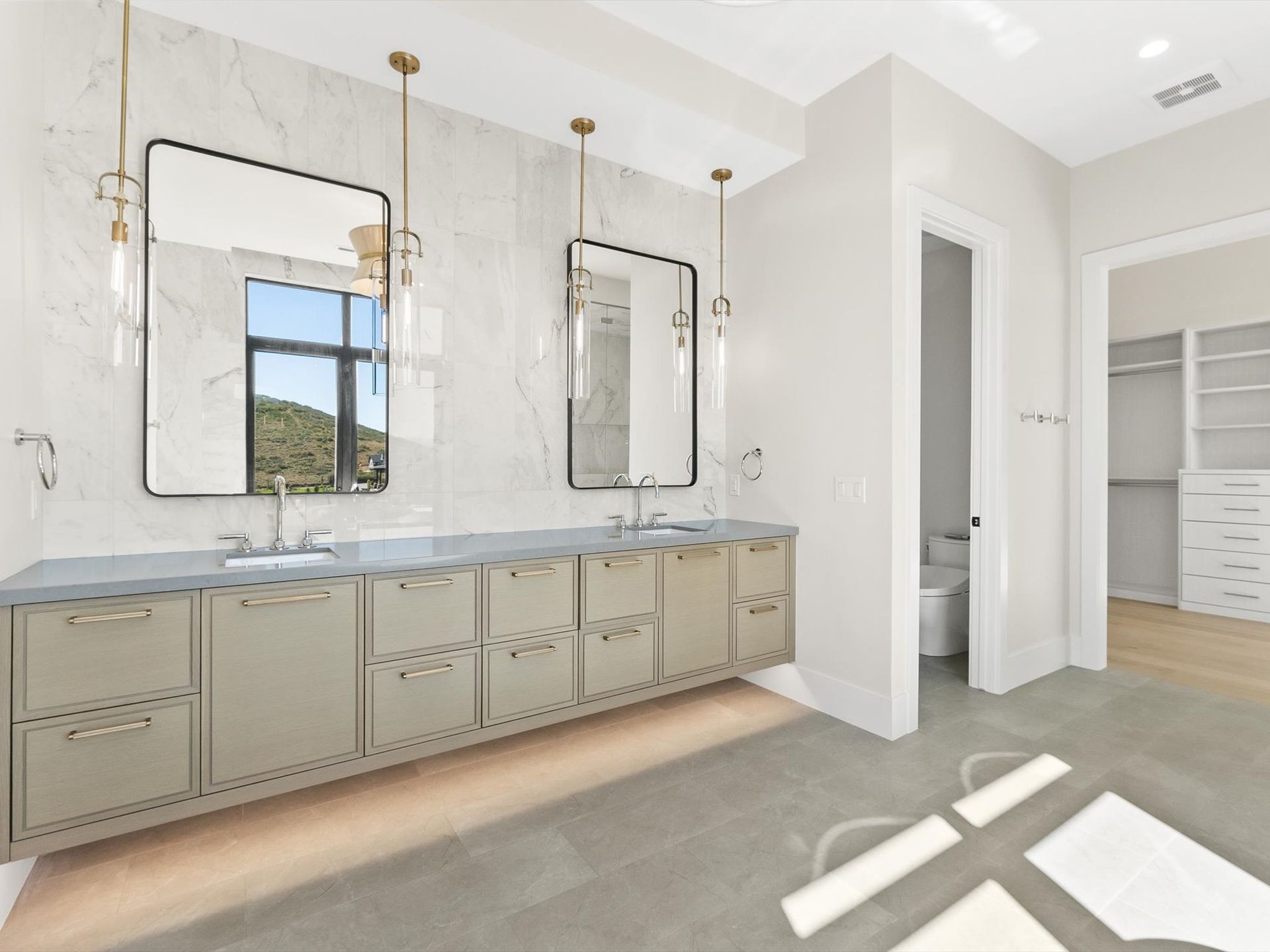 A bathroom with two sinks , two mirrors and a toilet.