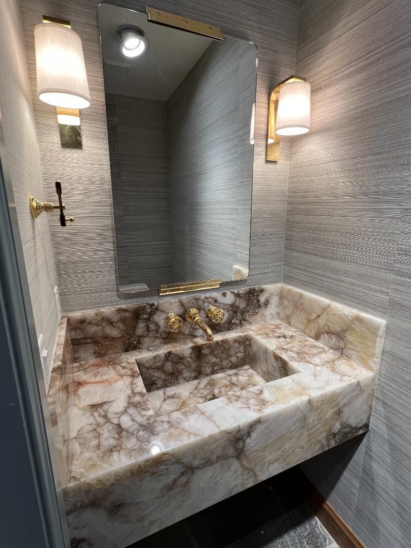A bathroom with a sink , mirror and lights.