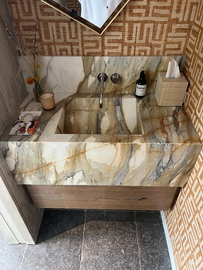 A bathroom sink with a marble counter top and a mirror.