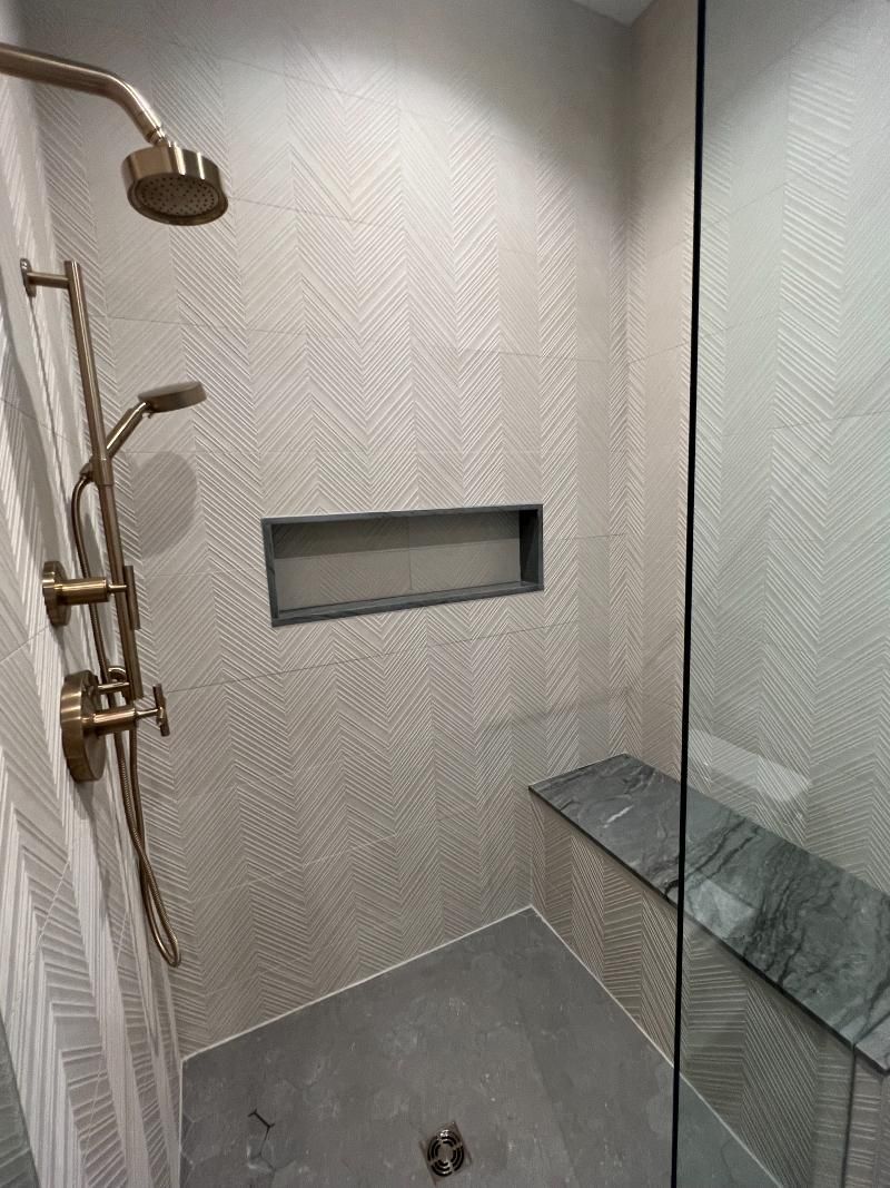 A walk in shower with a bench and a shower head.