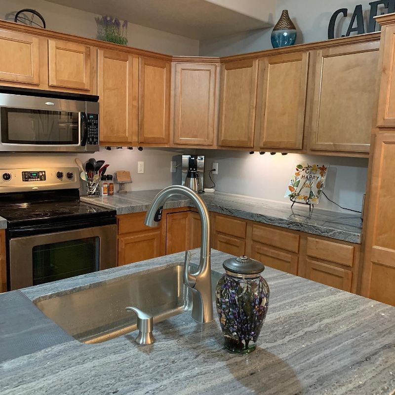 A kitchen with a sink , stove , microwave , and wooden cabinets.