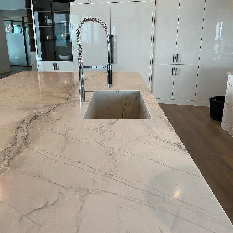A kitchen with a marble counter top and a sink.