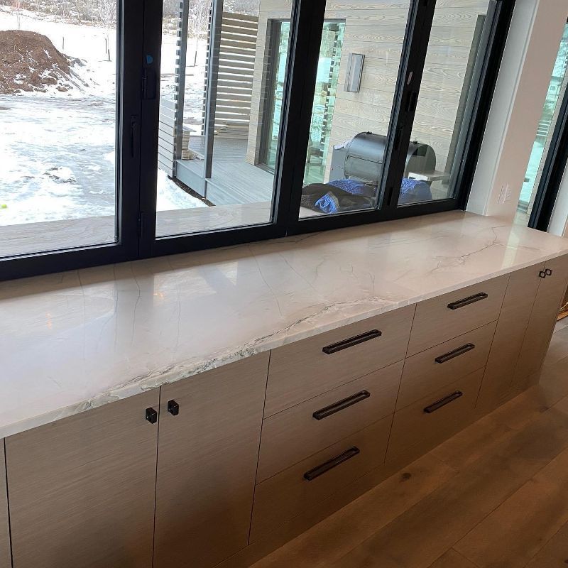 A kitchen with a large window and a marble counter top.