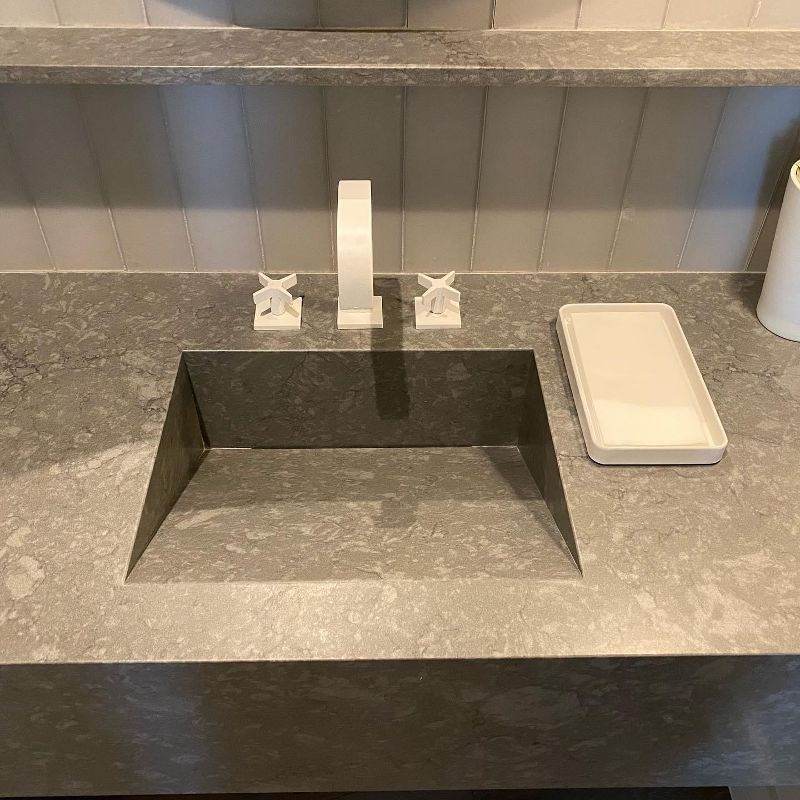 A bathroom sink with a faucet and a tray on the counter.